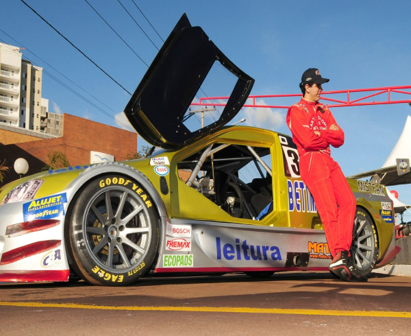 Race driver standing beside a race car